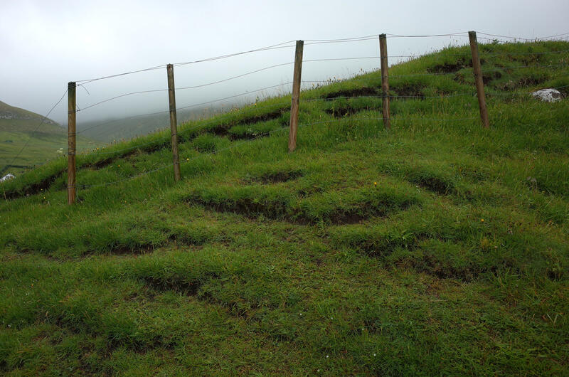 Grassy hill and a old wire fence in Gjógv