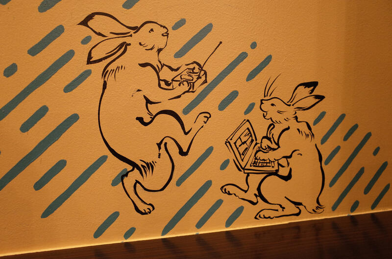 Drawn illustrations of two rabbits using computers and mobile phones