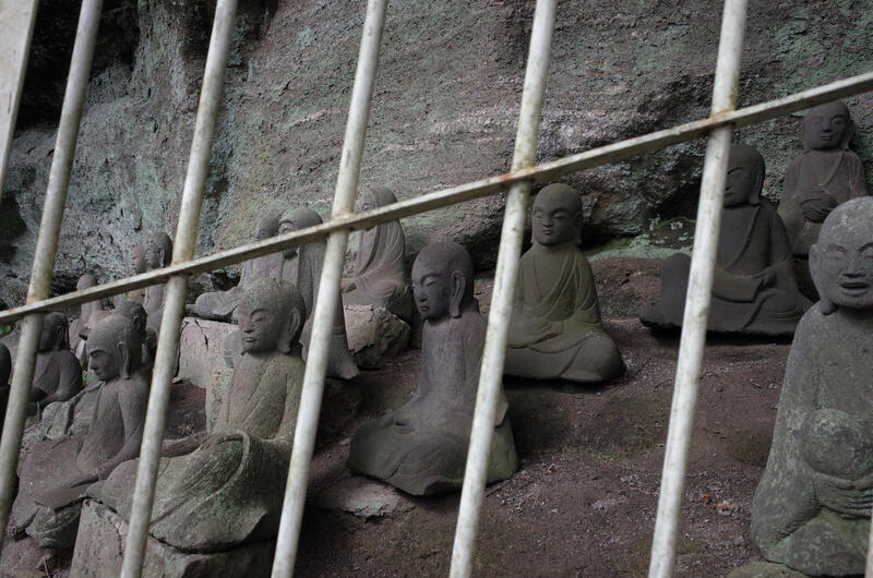 Small Buddha statues behind a fence