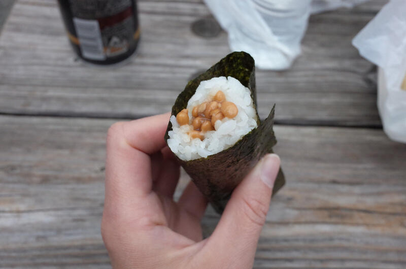 A hand holding a delicious natto roll