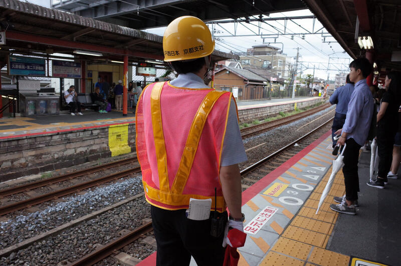 A worker in a hardhat and hi-wiz west at the railway platform