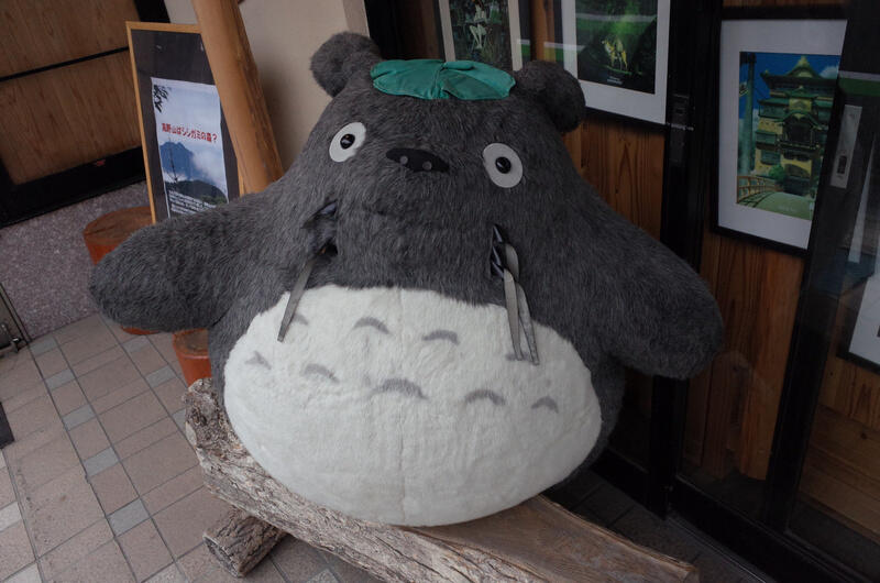 A large Totoro plushie standing near a doorway